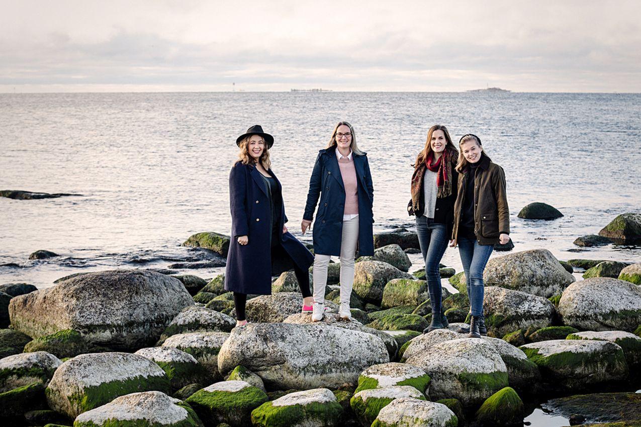Fyra kvinnor står på strandstenar