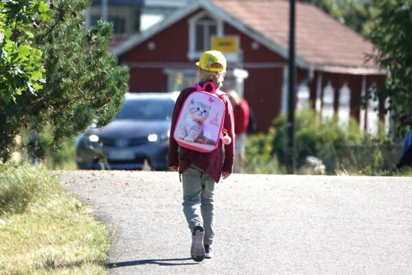 barn med gul skärmmössa och ryggsäck på ryggen