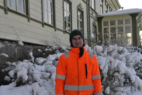 Man framför stort trähus. Vinter.