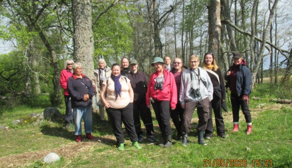 En grupp med människor ler mot kameran. Bilden är tagen utomhus på våren, solen skiner och omgivningen är grön.