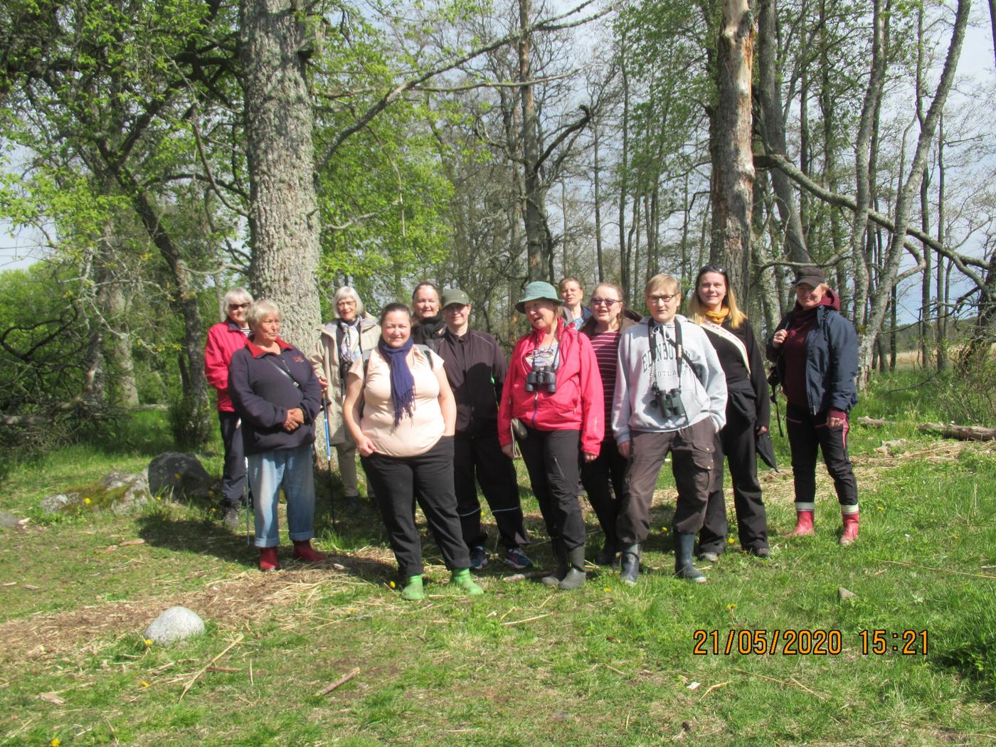 En grupp med människor ler mot kameran. Bilden är tagen utomhus på våren, solen skiner och omgivningen är grön.