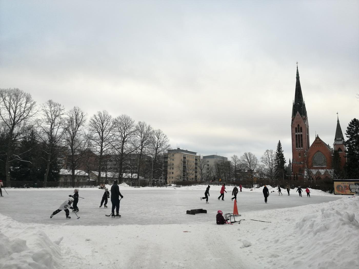 En skridskobana fylld av folk. I bakgrunden syns Mikaelskyrkan.