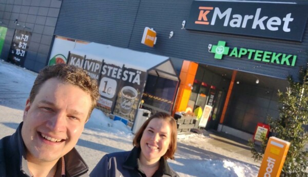 Två glada köpmän framför en butik.