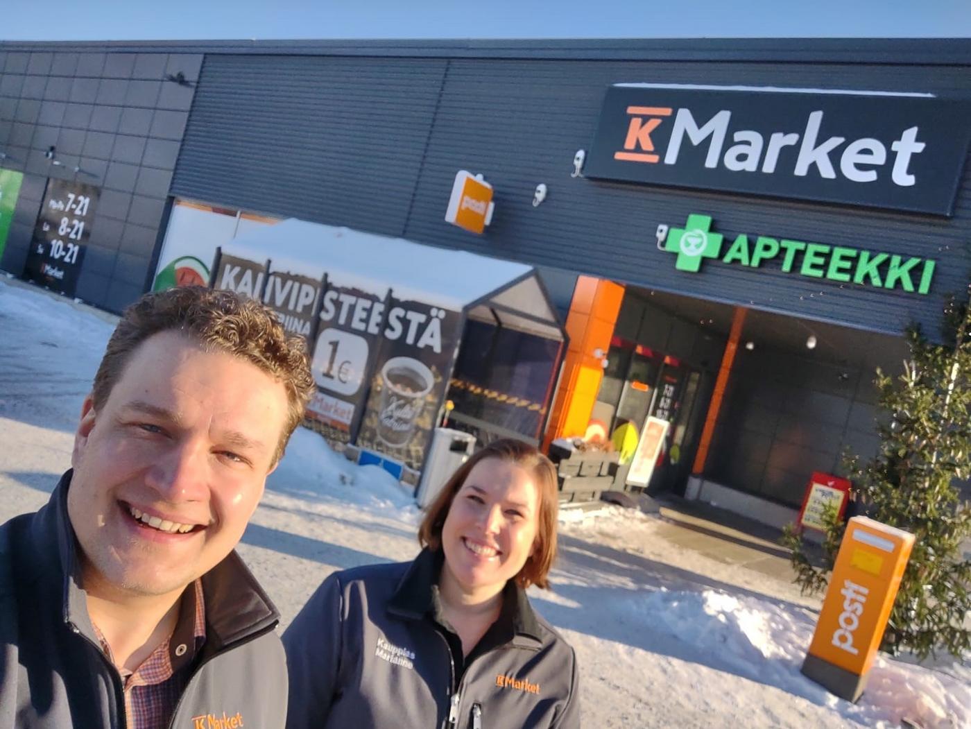 Två glada köpmän framför en butik.