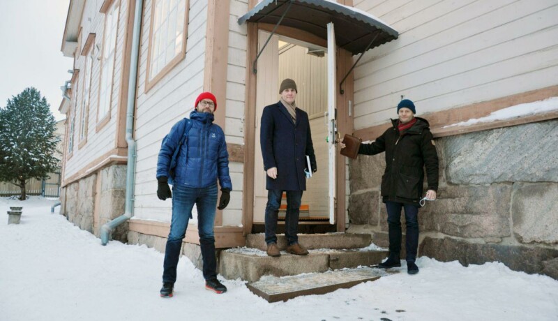 Tre män står vid skoltrappa