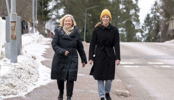 två damer promenerar längs med gata
