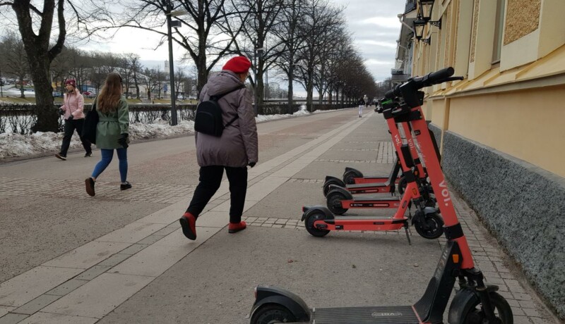 personer spatserar förbi elsparkcyklar vid åstrand