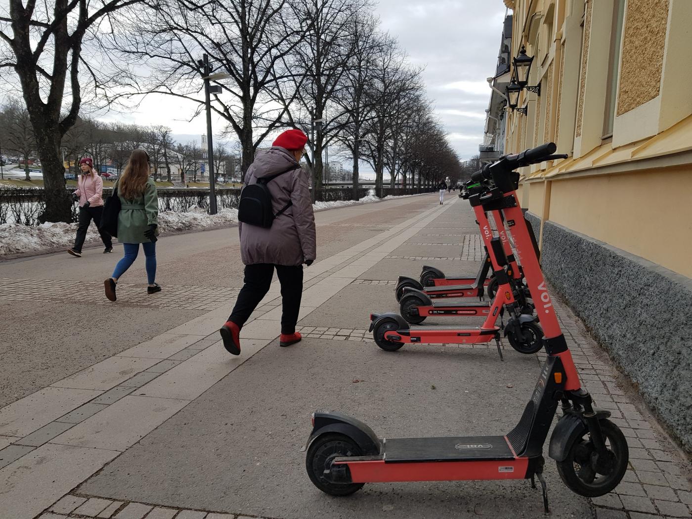 personer spatserar förbi elsparkcyklar vid åstrand