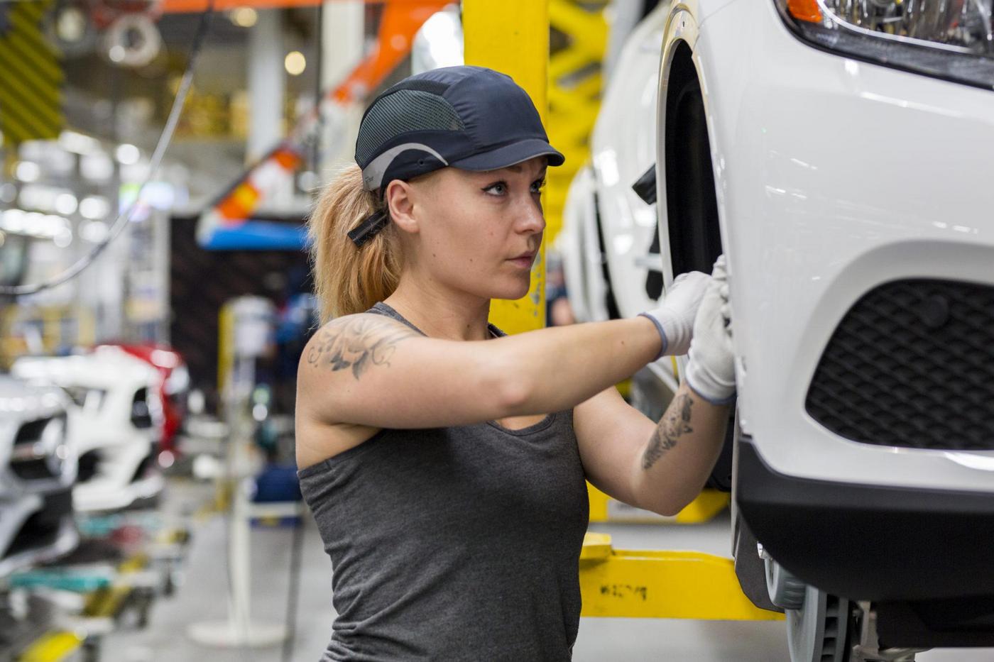 Kvinna som gör något på en bil i en fabrik.