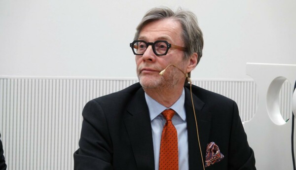 en man med slips och kavaj sitter med en mikrofon