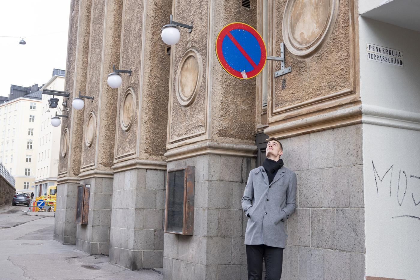 en lång man står under ett trafikmärke