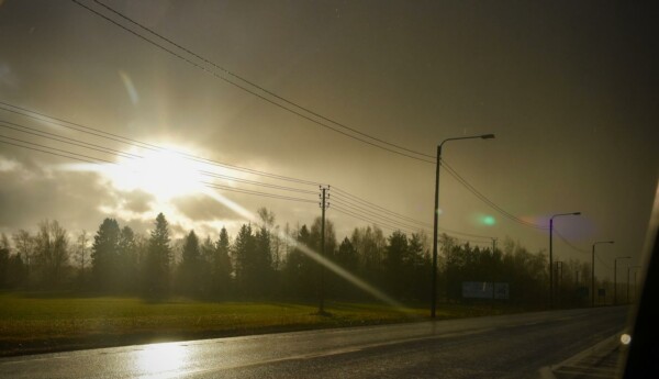 solen skiner igenom molnen på en regning landsväg