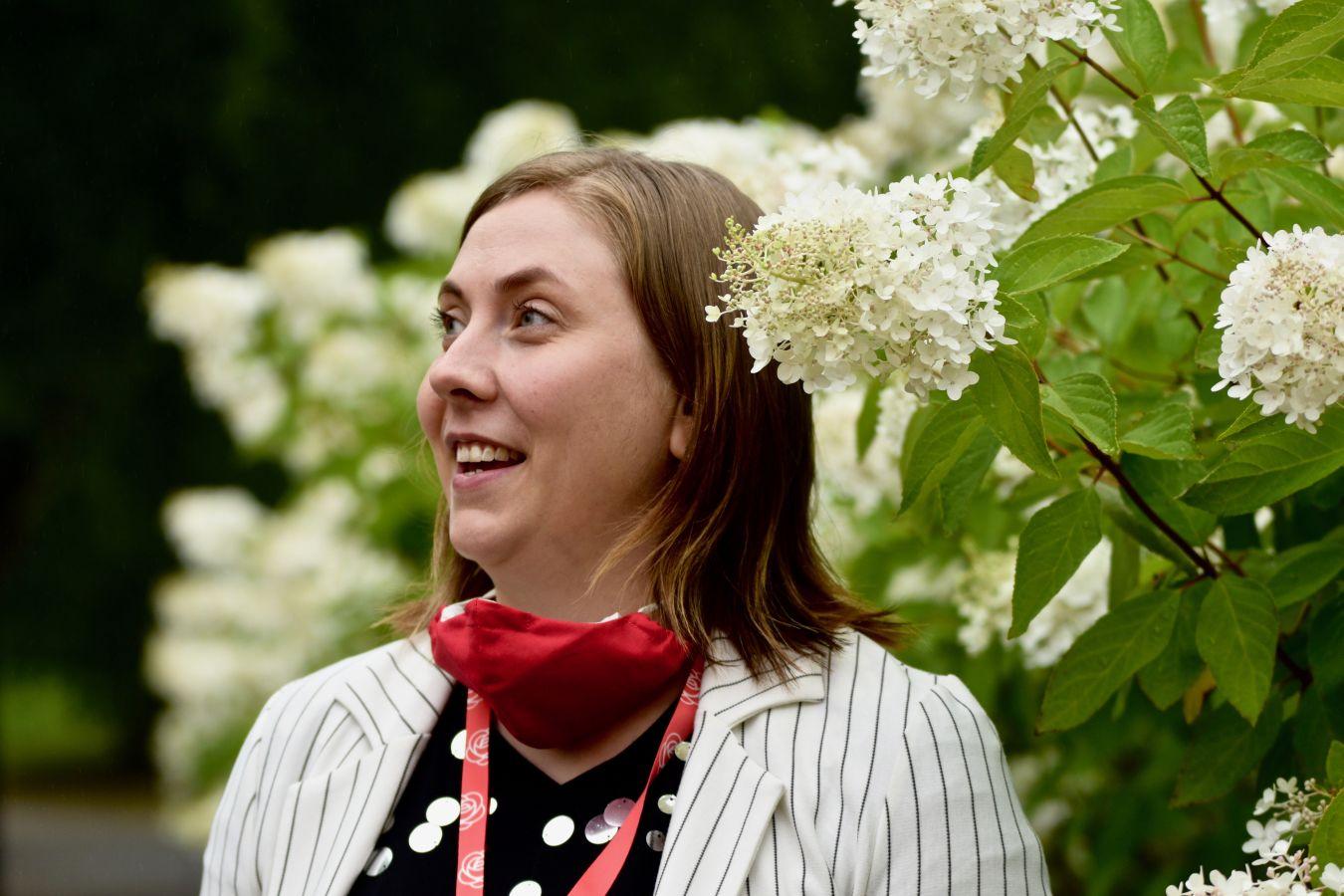 Glad kvinna vid blommande syrenbuske
