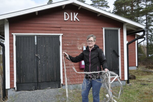 Dam med ett nät i handen vid en sportstuga