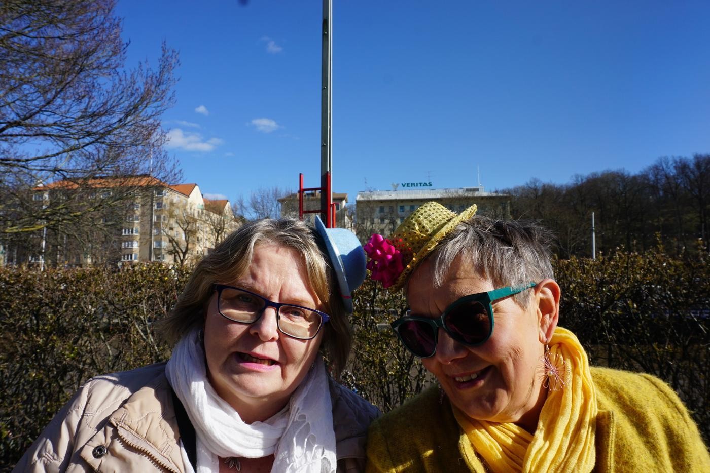 två glada kvinnor med små hattar på huvet