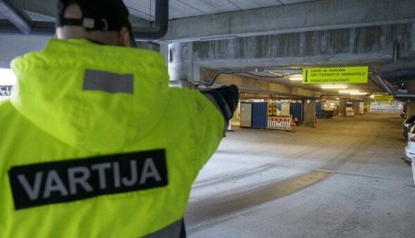 väktare dirigerar i riktning mot coronatest i parkeringshall