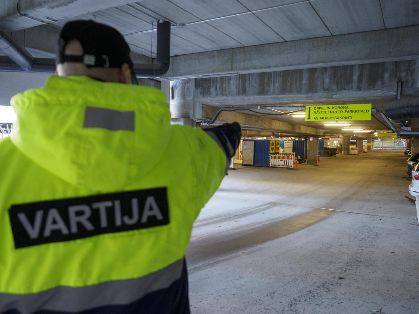 väktare dirigerar i riktning mot coronatest i parkeringshall