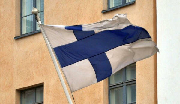 Finlands flagga vajar i flaggstång på husvägg