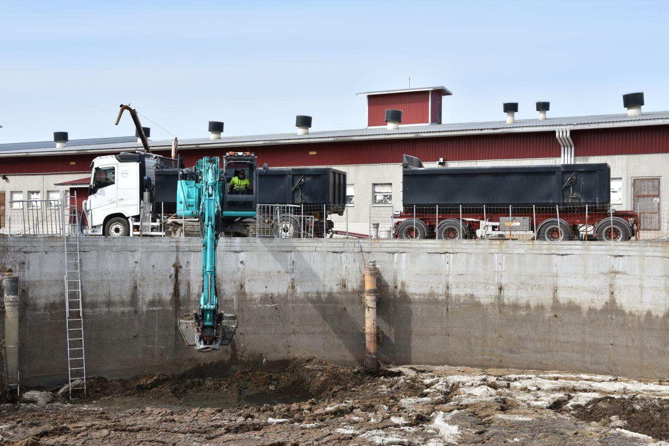 Grävmaskin lyfter dynga från en bassäng