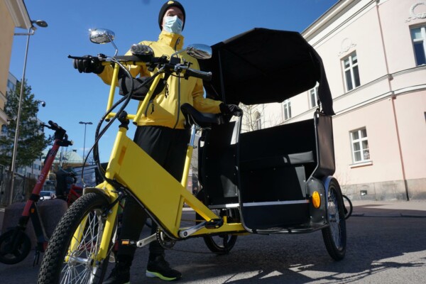 en gul cykelriksha och en gulklädd chaufför som står vid den