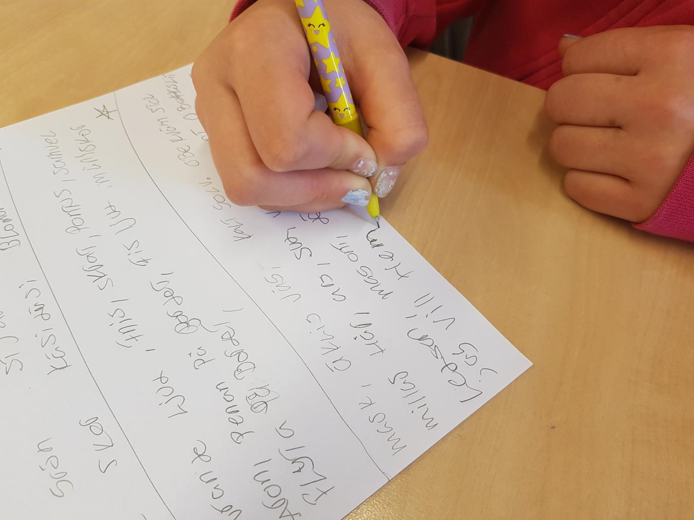 Hand som skriver på papper fyllt med text