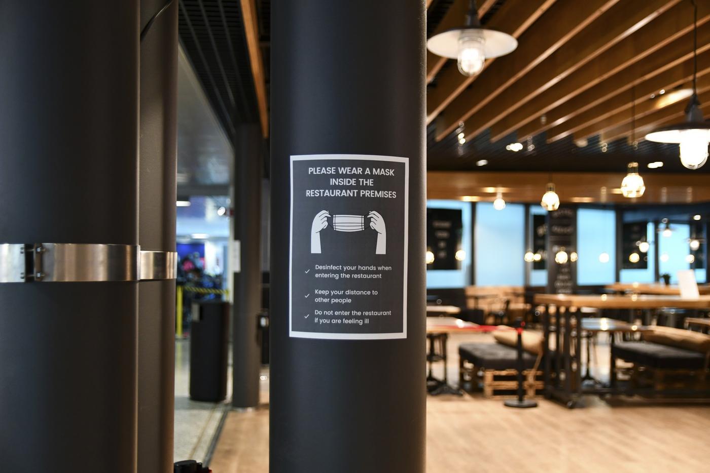 En skylt i en restaurang som visar att man ska ha munskydd på sig.