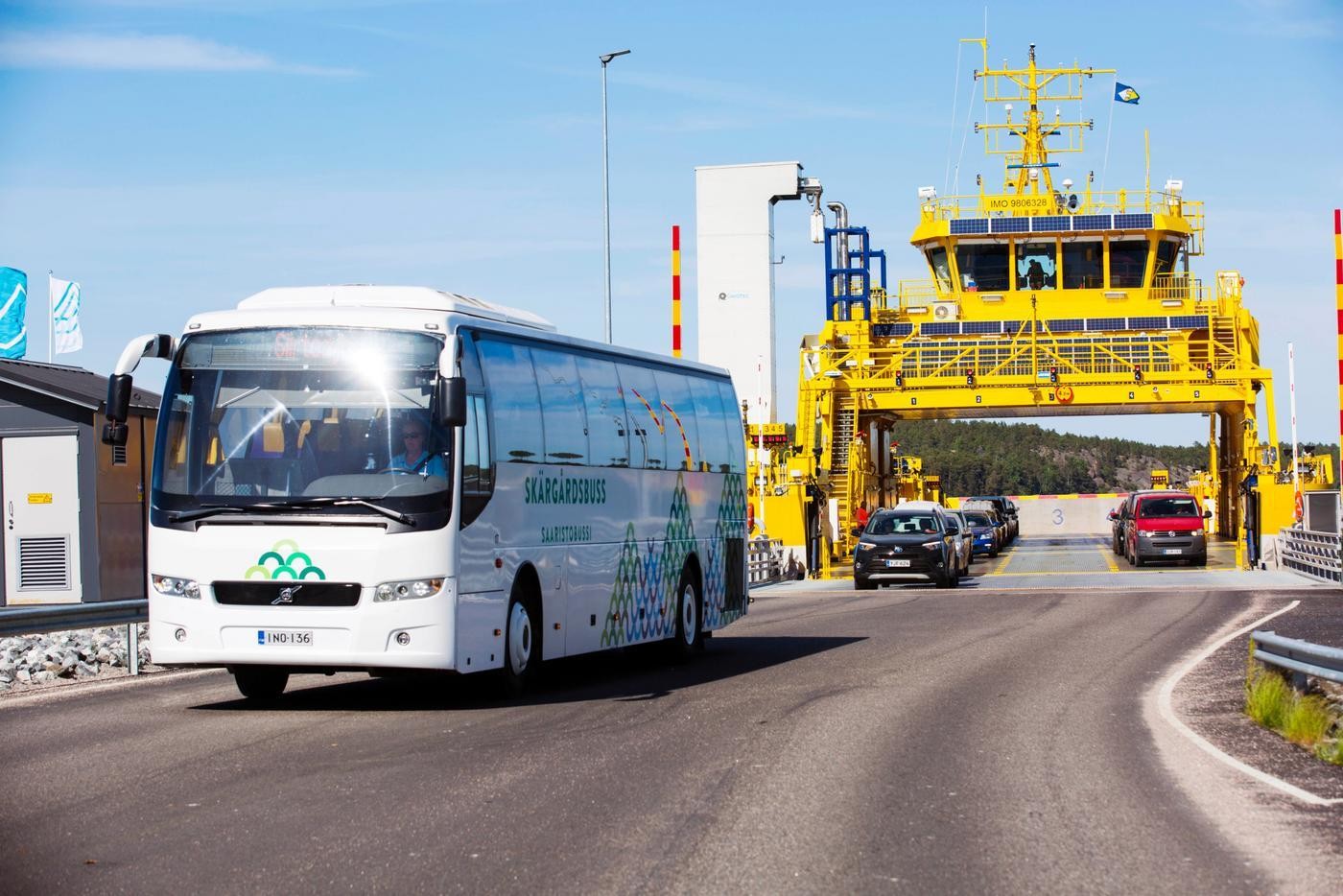 En buss kör just av en färja. Det är en solig dag.