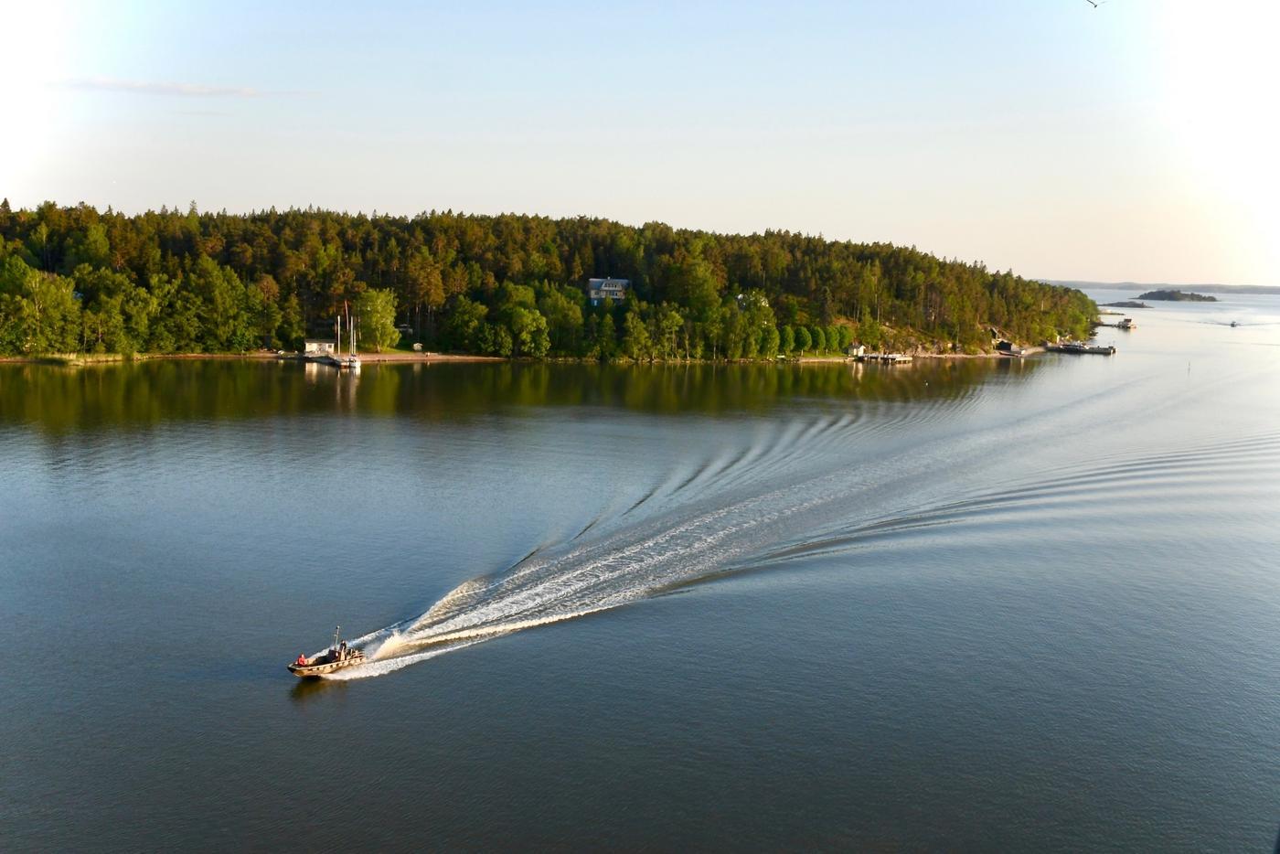 En motorbåt som kör över ett spegelblankt hav.