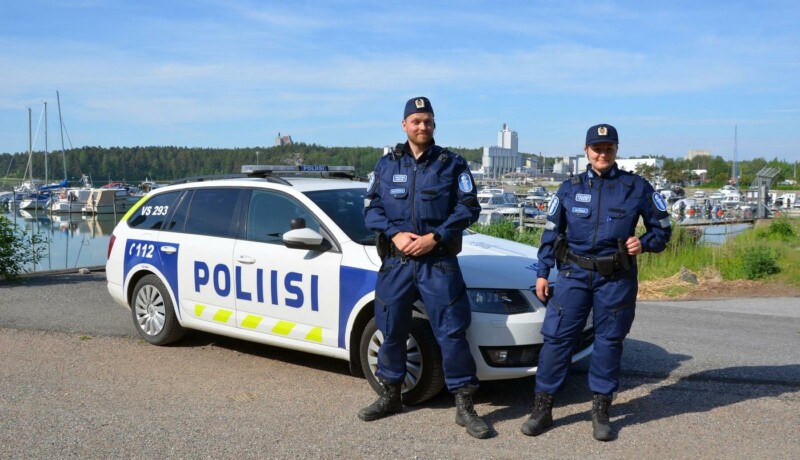 två poliser framför en polisbil i skärgårdsmiljö