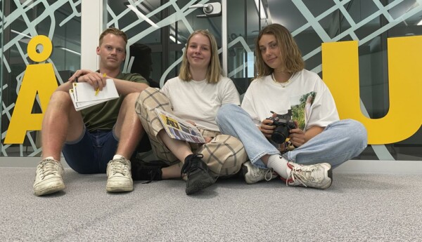 Sommarreportarna 2021 sitter alla tre på golvet mellan bokstäverna Å och U. Alla tittar in i kameran.
