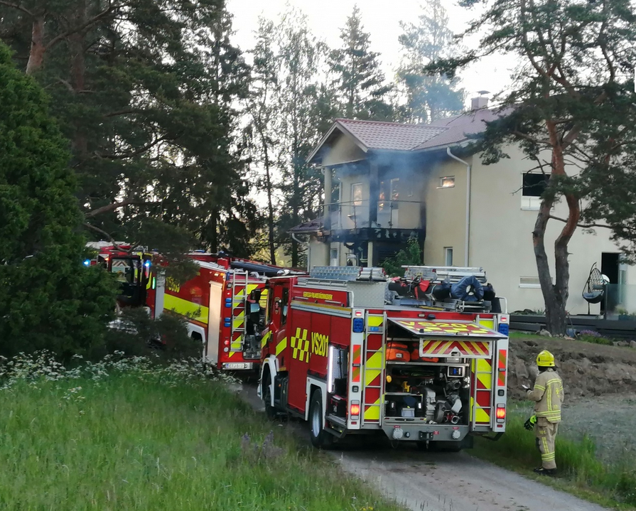 en rykande bralkong på ett egnahemshus, brandbilar parkerade nedanför