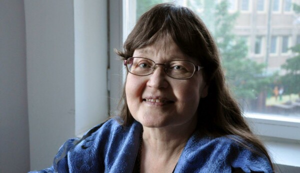 Kvinna med glasögon sitter vid fönster