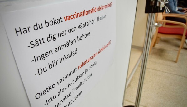 En illustrationsbild med en skylt med instruktioner om coronavaccinering.
