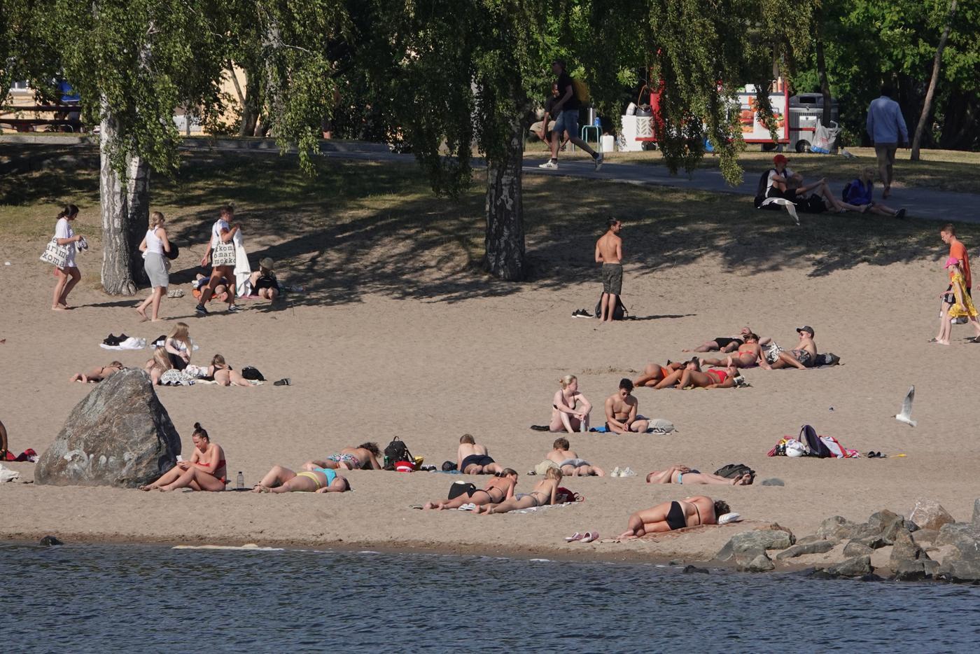 En badstrand med människor som solar. 