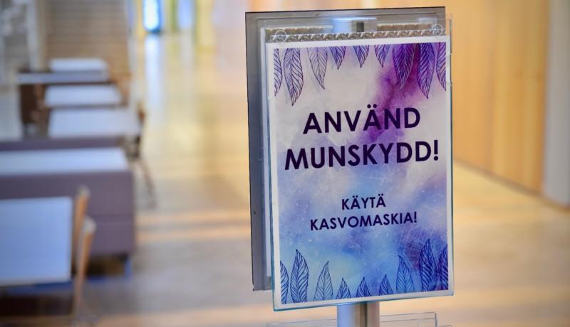 En skylt där det står "Använd munskydd!"
