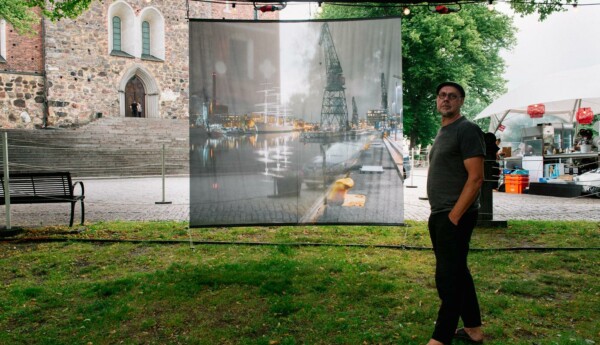 En man vid ett stort fotografi i en park.