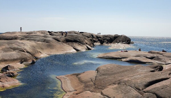 klippor vid havet människor ses vandra och bada vid klipporna