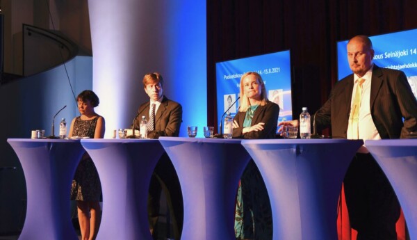 Fyra personer står i rad vid talarstolar på en paneldebatt.