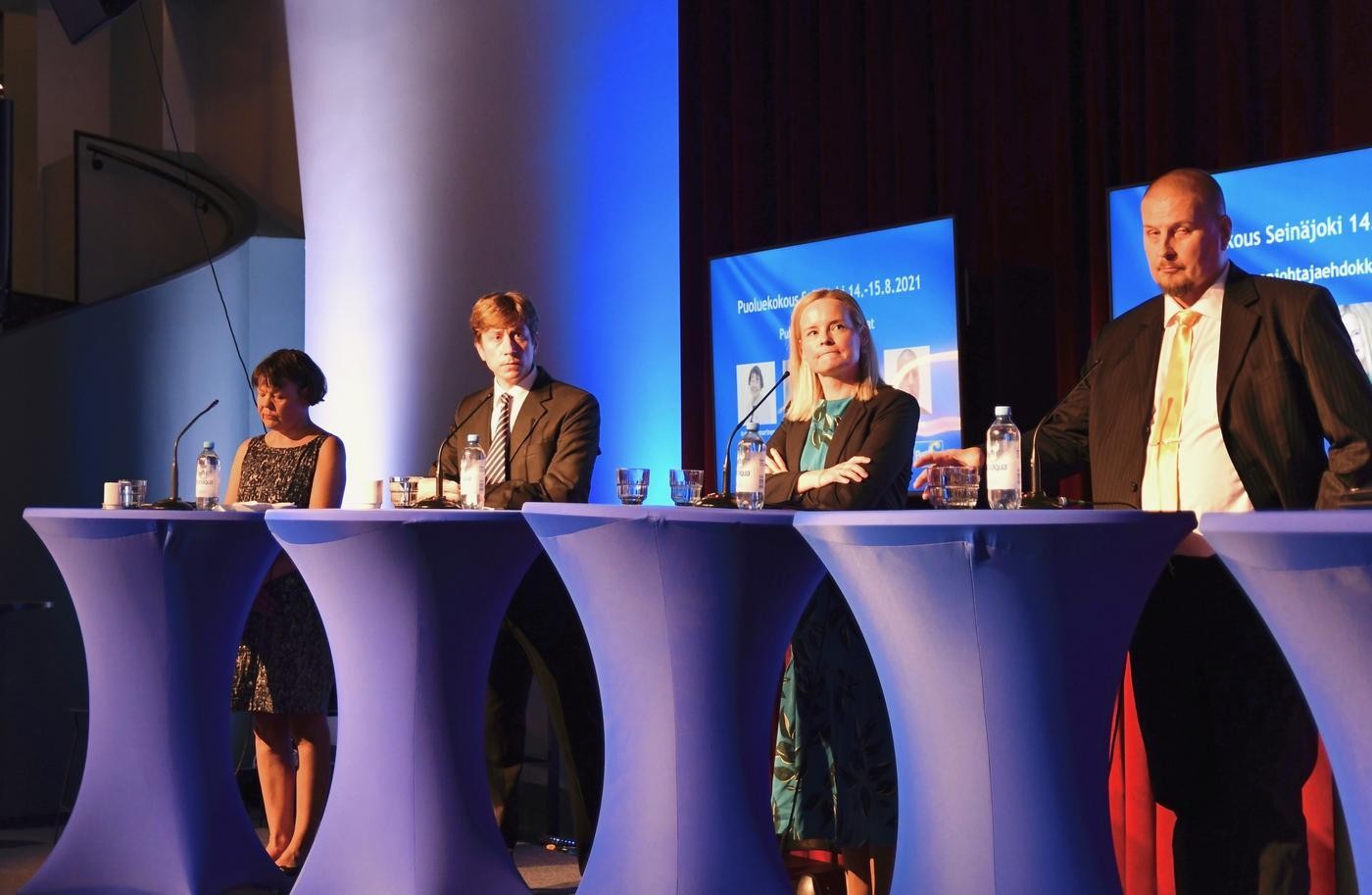 Fyra personer står i rad vid talarstolar på en paneldebatt.