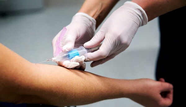 Ett par händer som vaccinerar en arm.