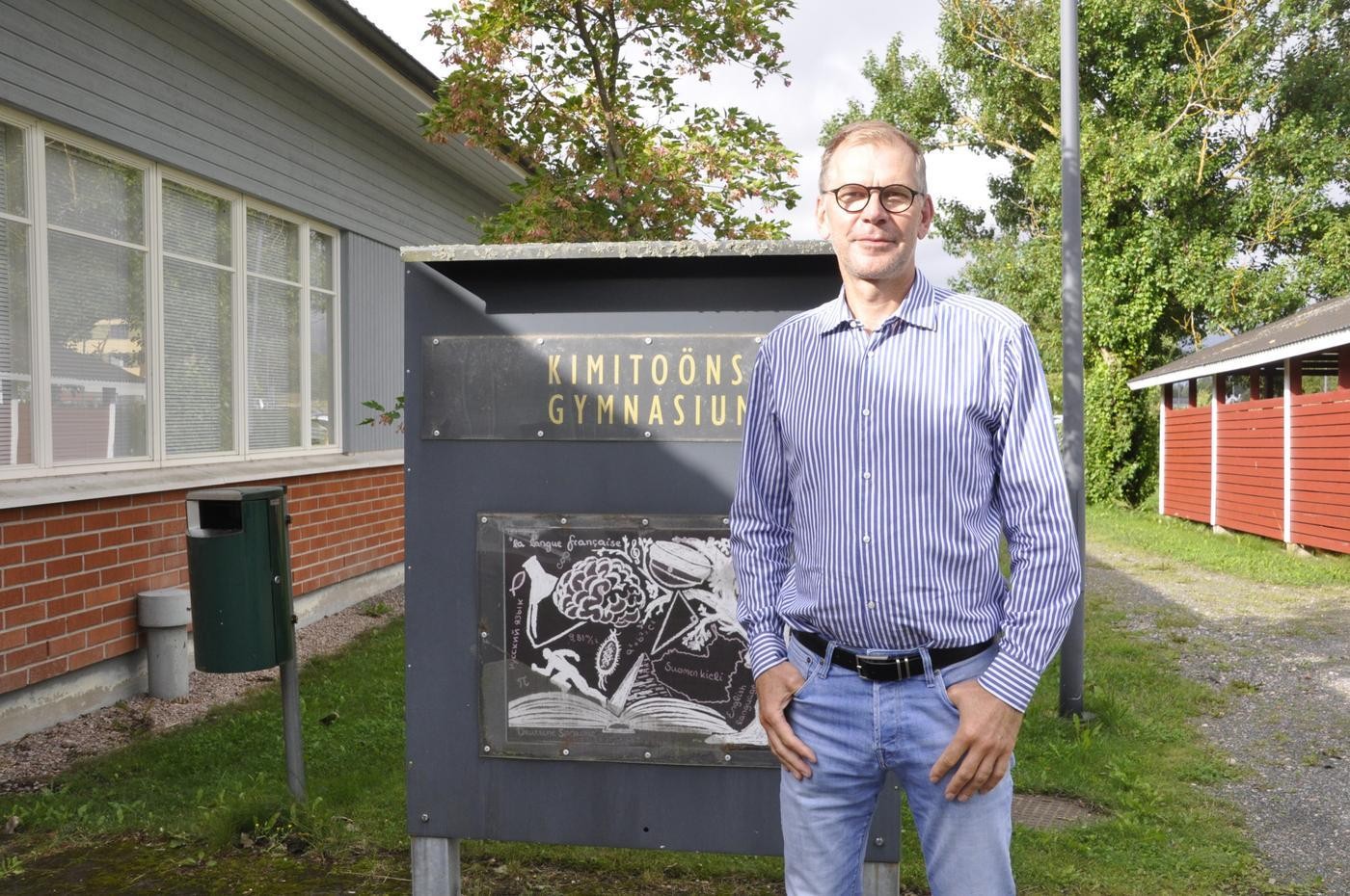 Man vid en skylt med texten Kimitoöns gymnasium