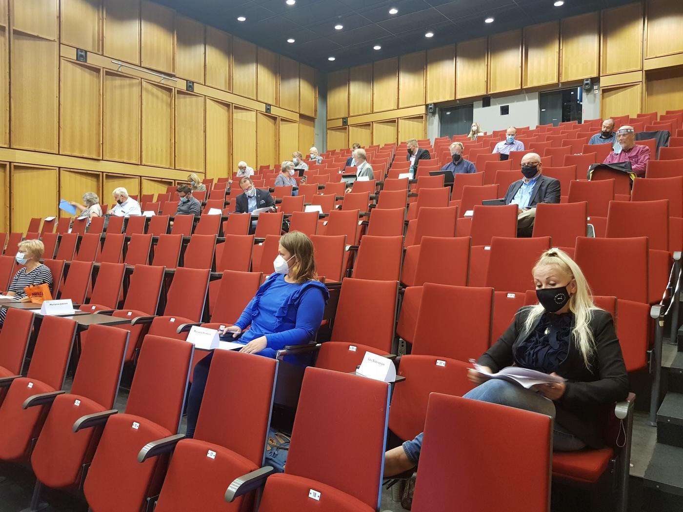 auditorium där mötesdeltagare sitter med rejäla mellanrum