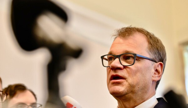 man med glasögon framför mikrofoner
