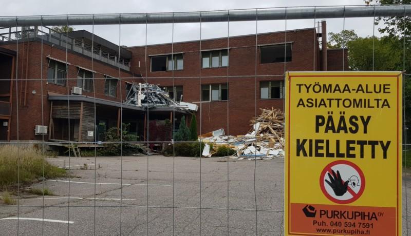 ingärdad tegelbyggnad, med förbudsskylt. Rivningsmaterial utanför fönstren.