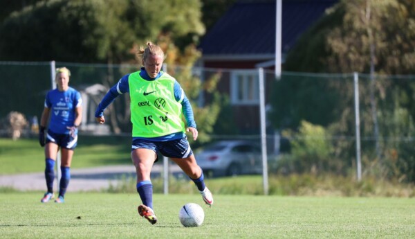 kvinna springer med fotboll på fotboll på plan