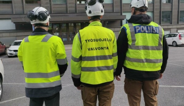 tre personer med reflexvästar på står med ryggarna mot kameran