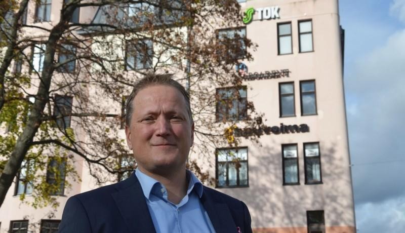 Man i kavaj står framför gammalt stenhus