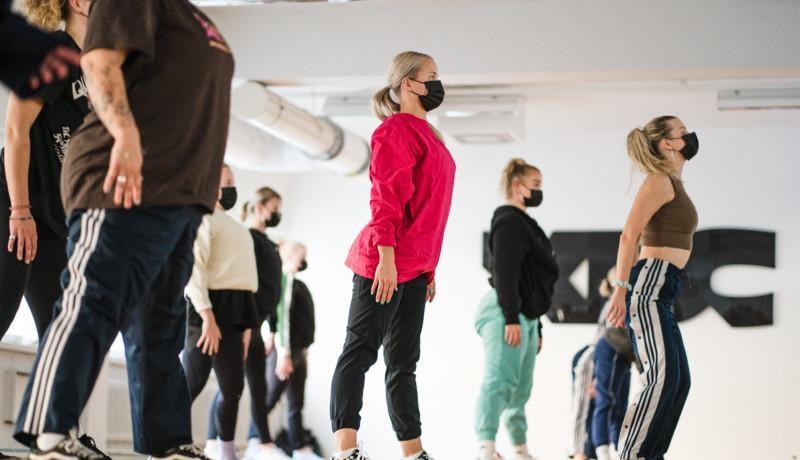 En grupp dansare i en sal, de har på sig munnskydd