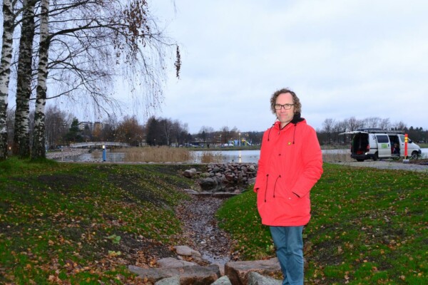 en man i röd jacka står vid ett dike