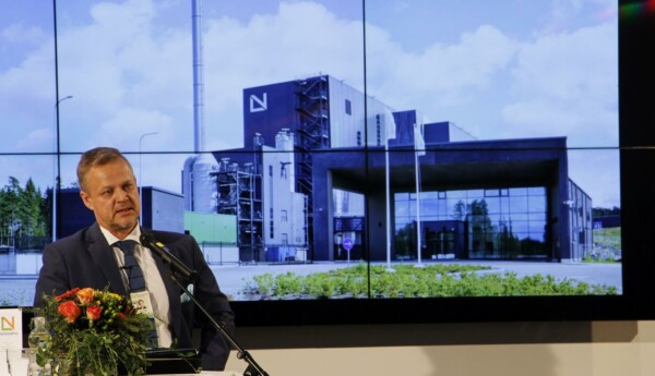 Man håller tal. Stor bild i bakgrunden av byggnad